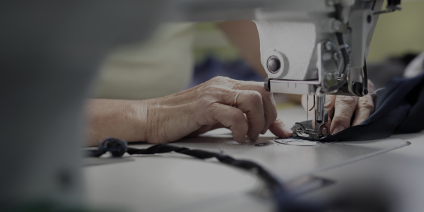 Close-up of tailor's hands sewing a garment with a 'Made in Japan' label, symbolizing excellence.